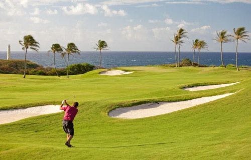 A man in a red short playing golf on a Caribbean island