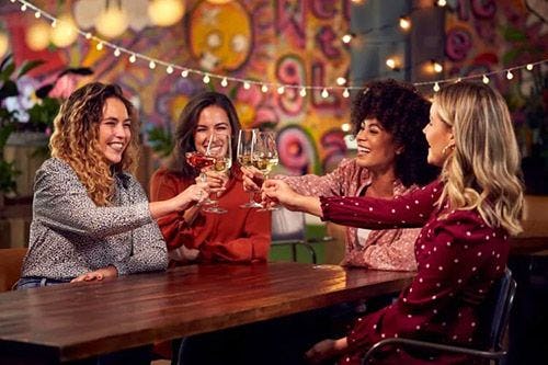 Four friends clinking wine glasses in a bar 