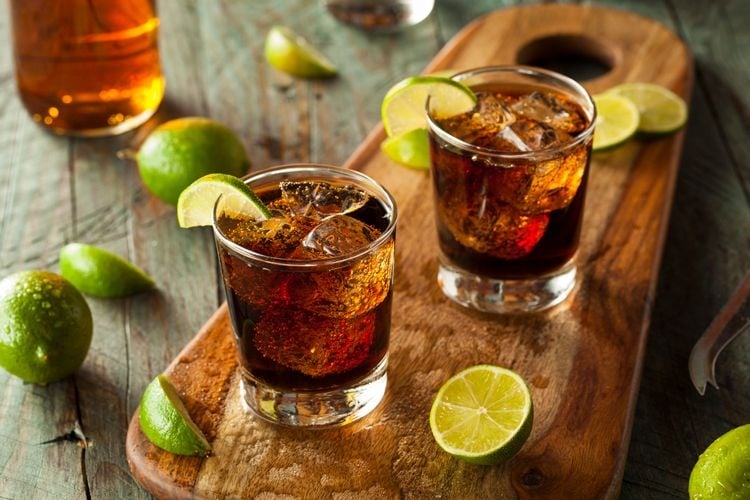 A wooden board with two glasses of rum and coke