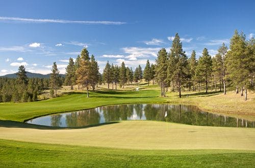 Golf course in Montana with small lake and mountains in the background