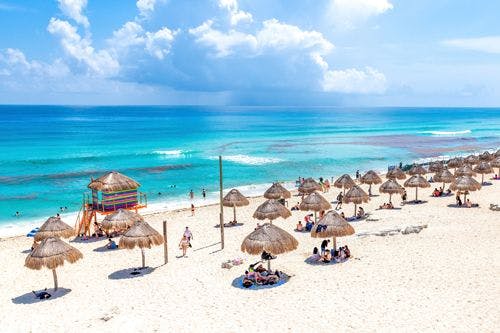 A white sand beach with grass parasols on a Cancun beach