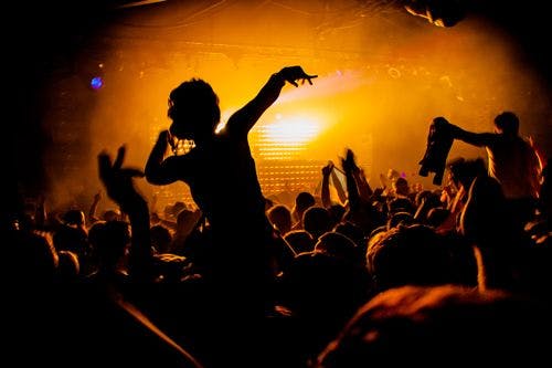 A woman on someone's shoulders in a crowd at a nightclub