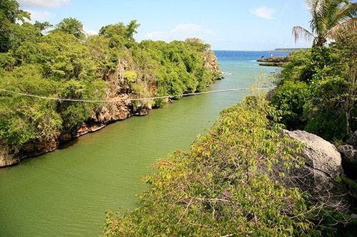 A river with forests on either bank flowing to the sea in Boca de Yuma, Dominican Republic