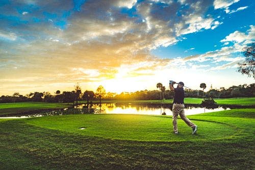 A man playing golf on a Florida golf course at sunset