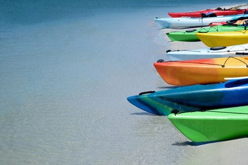 Colorful kayaks lined up along a white sand beach
