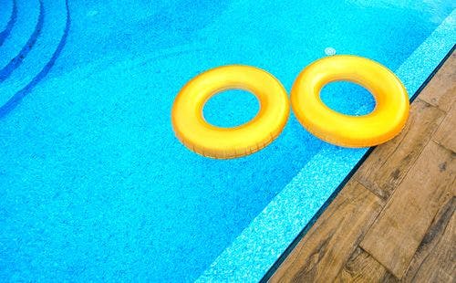 Two yellow inflatable donuts in a swimming pool