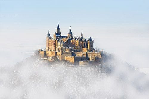 A German castle on top of a hill shrouded in fog