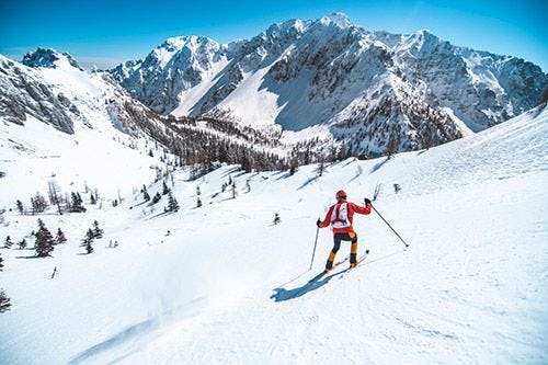 A man in a red outfit skiing in the Alps