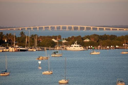 Small fishing boats moored off Sanibel Island with large bridge in background