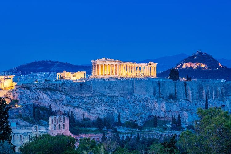 The Acropolis and ancient Parthenon building on a hill overlooking Athens at night