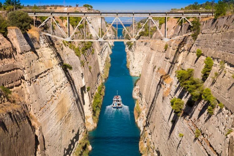 The Corinth Canal - a manmade river through a large gorge with a boat sailing through it