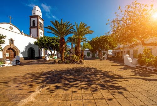 Central square in Arrecife, with palm trees, and a white painted colonial-style church
