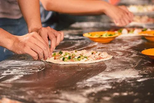 People making pizza on a floured table