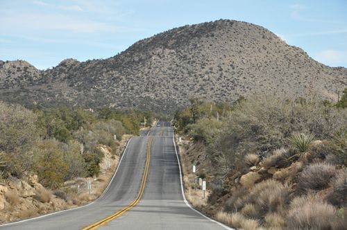 A long road undulating through a mountainous desert landscape