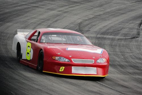 A red and white car racing around a track