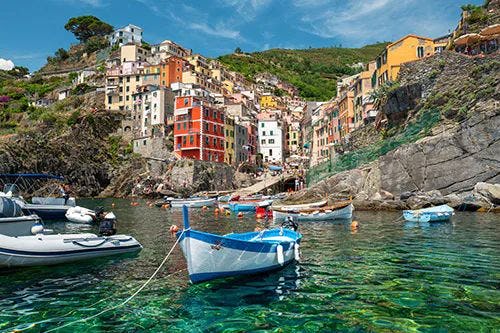 Fishing boats moored in the sea by one of the colorful Cinque Terre cliffside towns
