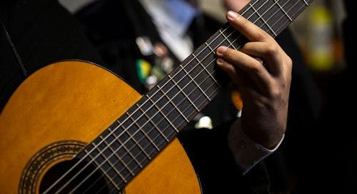 Close up of a man's hand playing an E Minor chord on a classical guitar