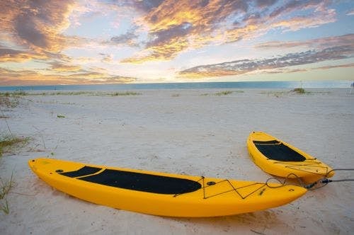 Two yellow kayaks on a white and beach
