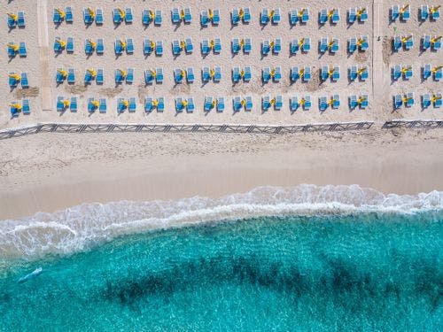 Aerial shot of blue sunbeds on a white sand beach