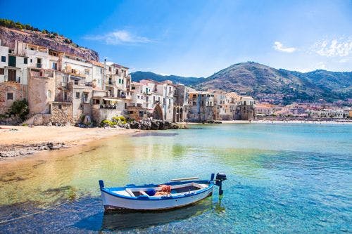 A small fishing boat moored in shallow water by Cefalu