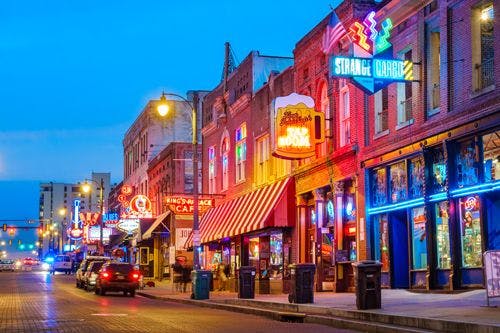 Night view of Beale Street in Memphis Tennessee with neon signs outside pubs and bars