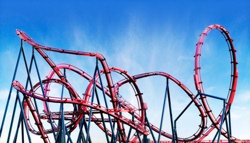 A red looping roller coaster against a blue sky