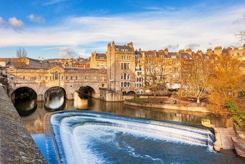 The weir in the River Avon with an ancient stone bridge in the city of Bath