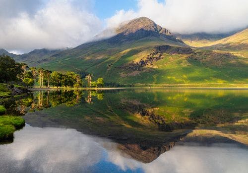 Reflection of a grassy mountain in a still lake in the Lake District