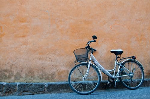 A bicycle leaning against an orange painted wall