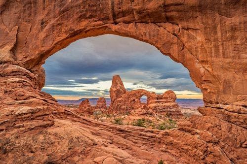 View of rock formations through a stone archway in Arches National Park