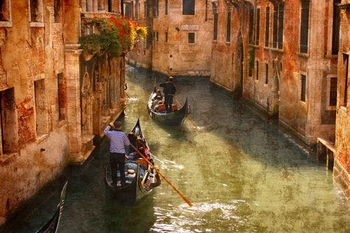 Two gondolas being rowed through a shallow Venice canal