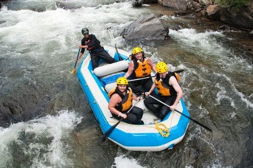 An inflatable raft with with people going down white water rapids