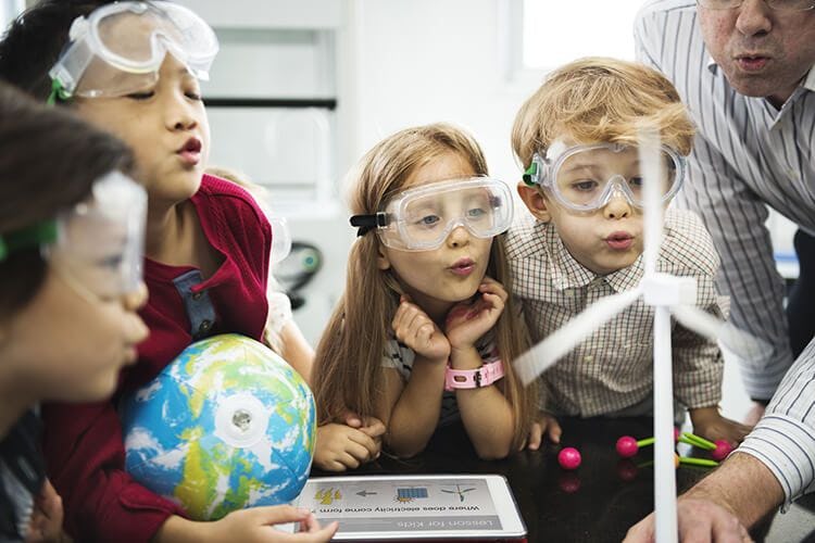 Children wearing safety glasses gathered around a science experiment in a museum