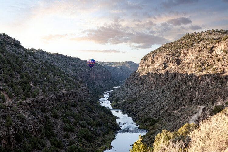 A hot air balloon glides silently over a gorge in Taos, New Mexico