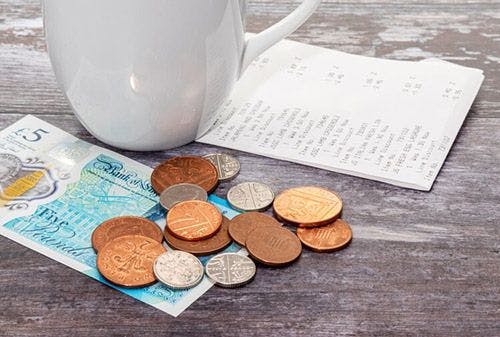 Euro notes and coins next to a coffee cup and receipt on table