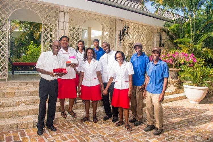 A team of housekeeping staff stand outside of a villa