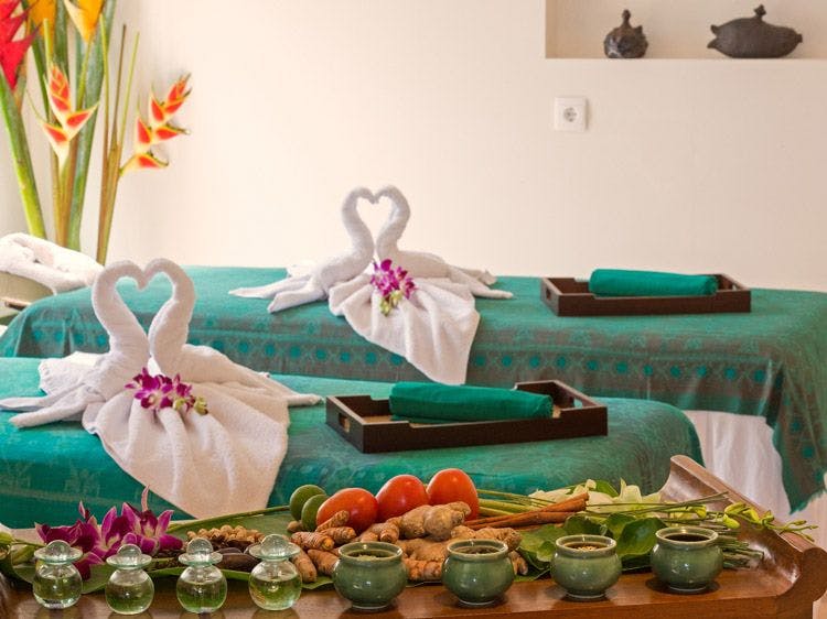 Two spa tables set with towel swans, petals, spa equipment