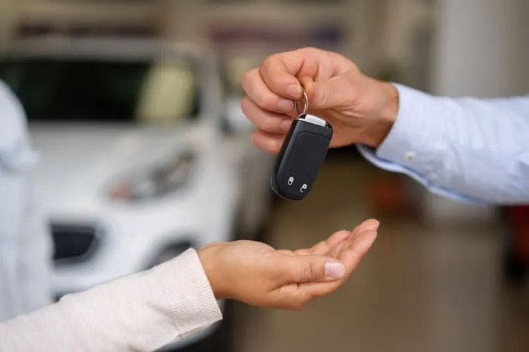 A man's hand giving a set of car keys to a woman's hand