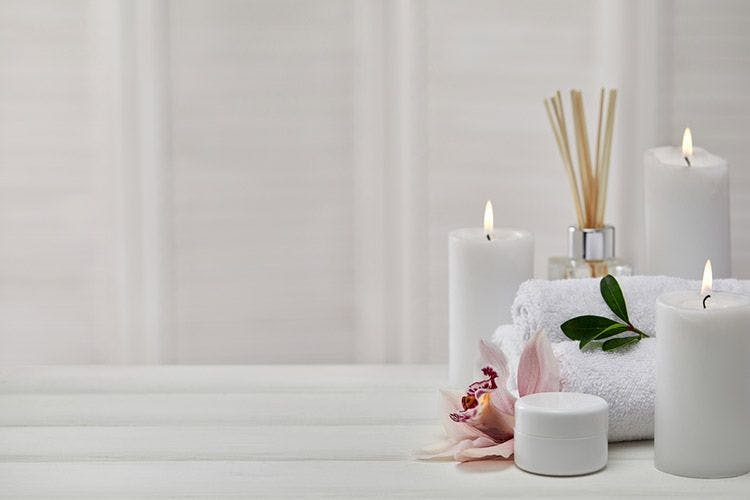 Spa objects including candles, reed diffusers, and lotion against a white backdrop
