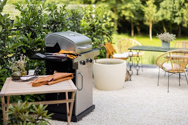 An outdoor barbeque grill with gloves and table