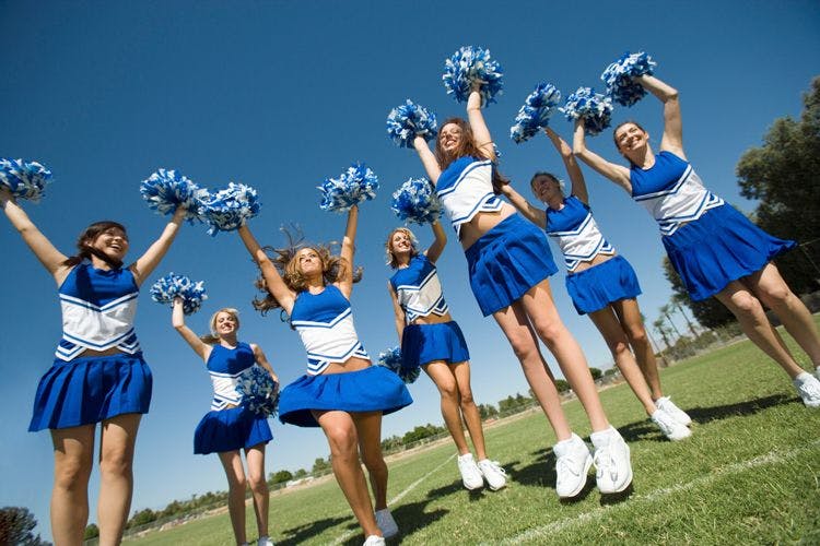 A cheerleading group jumping in a field