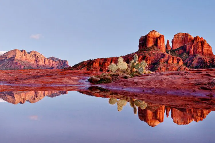 Rock formations and cacti in Arizona reflected in a lake