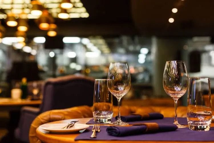 A table in a restaurant set with wine and water glasses and cutlery