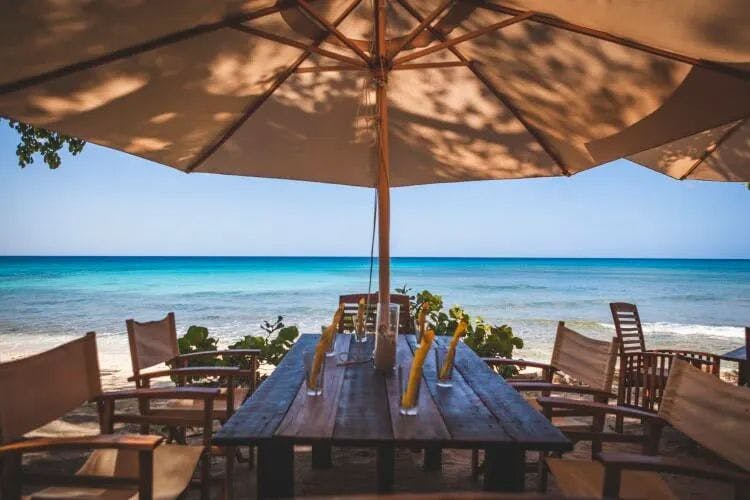 Wooden table, chairs and parasol on a beach by the sea