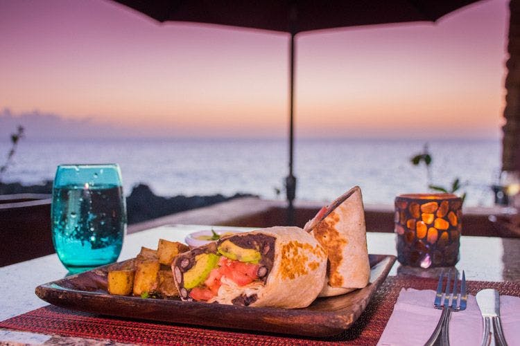 A burrito and glass at a restaurants by the sea