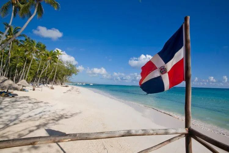 Dominican Republic flag on a white sand palm-fringed beach