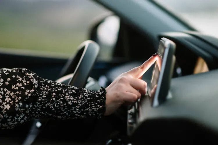 A woman pressing a GPS screen in a car