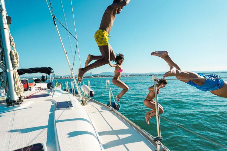 A group of people jumping from a yacht into the sea