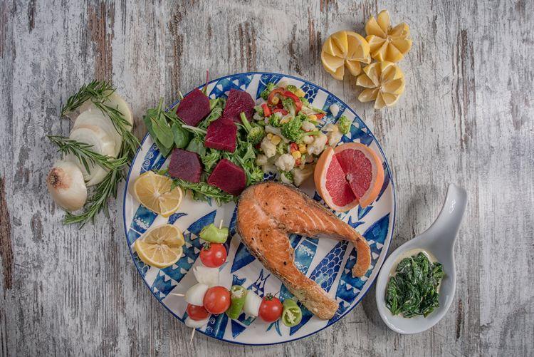 A blue and white plate of salmon and salad on a wooden table