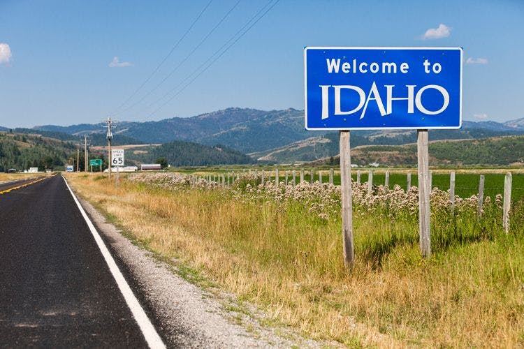 Road sin saying 'Welcome to Idaho' with mountains in the background